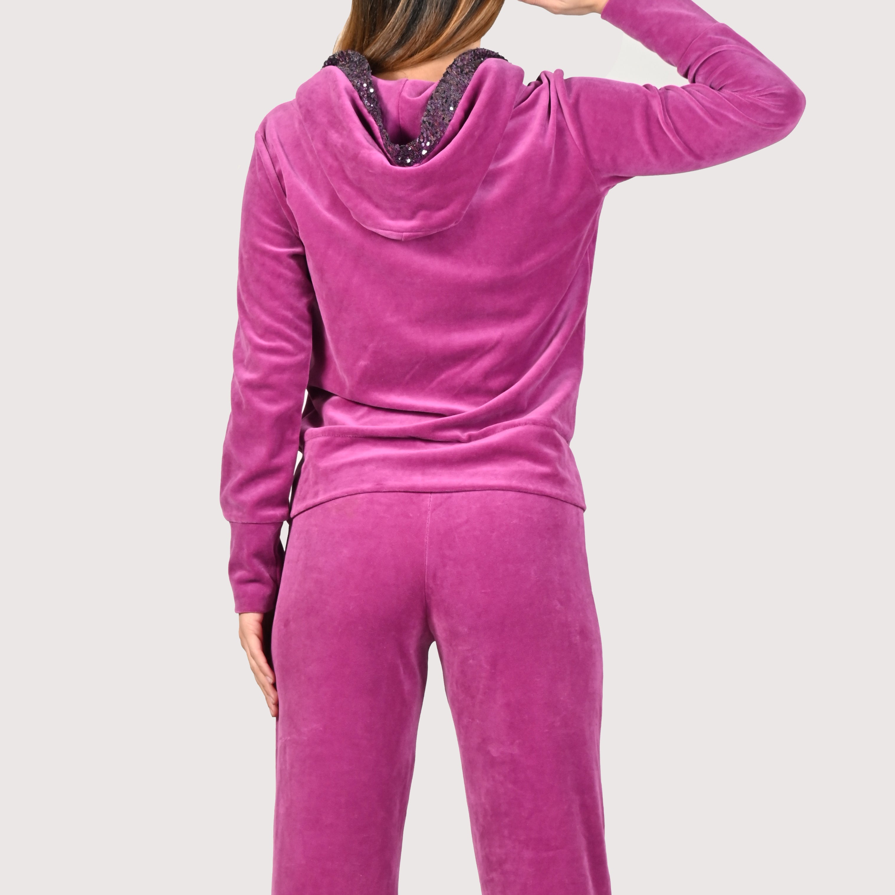 Tuta Completo in ciniglia fucsia sporty chic. La felpa con cappuccio è rifinita internamente e ha gli inserti in paillettes sul cappuccio e sulle tasche. Il pantalone morbido ha un'ottima vestibilità, con l'elastico in vita e la coulisse nell'orlo, per poter regolare la lunghezza del pantalone come si preferisce. Le tute in ciniglia e le tute da passeggio eleganti sono un'ottima alternativa per sentirsi sempre comode ed trendy. 