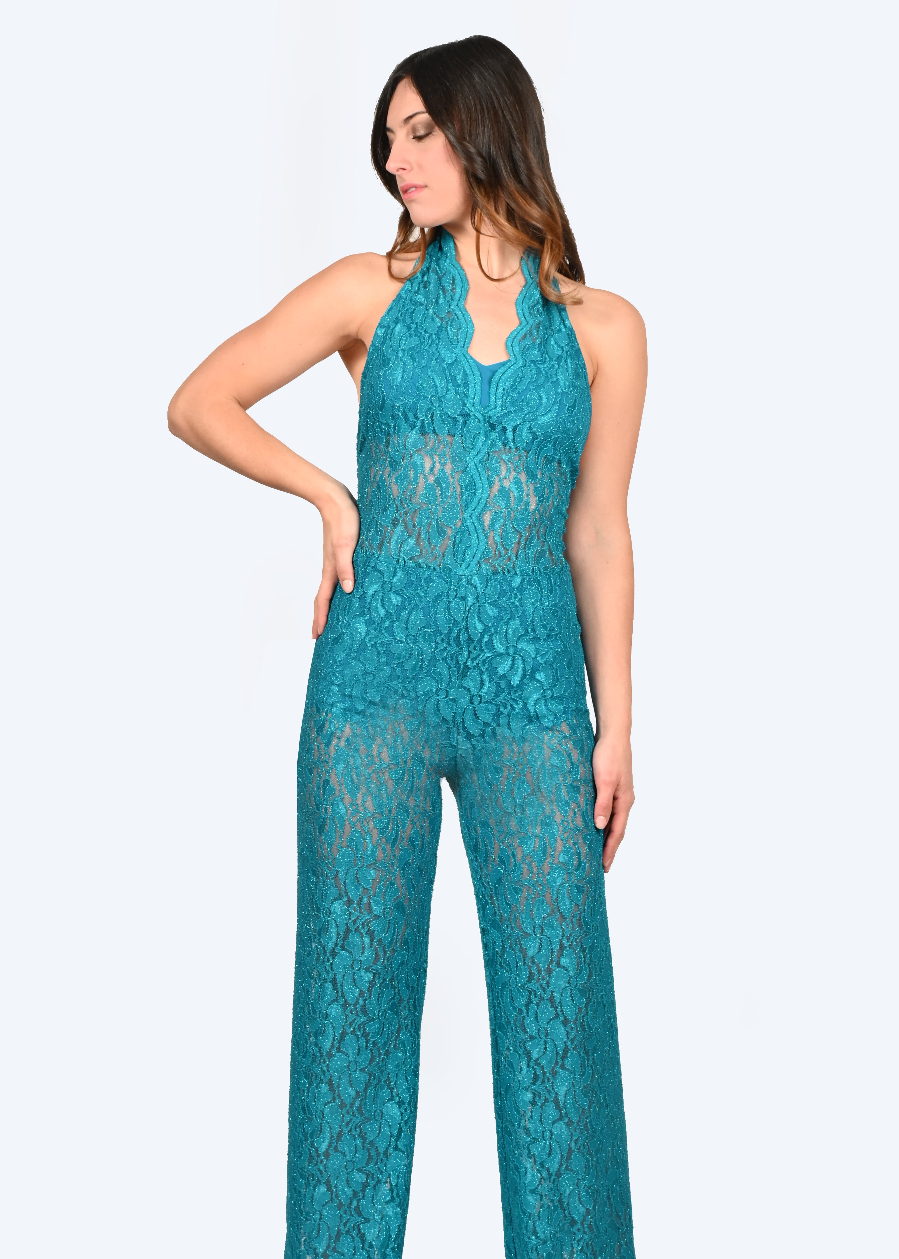 La tuta intera ottanio in pizzo Iris è caratterizzata da un profondo scollo a V lungo la schiena con cappiole e budellini incrociati regolabili. Il pizzo della jumpsuit elegante è impreziosito da un delicato effetto lurex, creando un sensuale effetto vedo non vedo. La tuta intera in pizzo ha la chiusura con bottone ricoperto dietro al collo, coppe estraibili ed è foderata internamente, lasciando l'addome scoperto. Il modello è a vita alta con pantalone dalla linea scivolata.