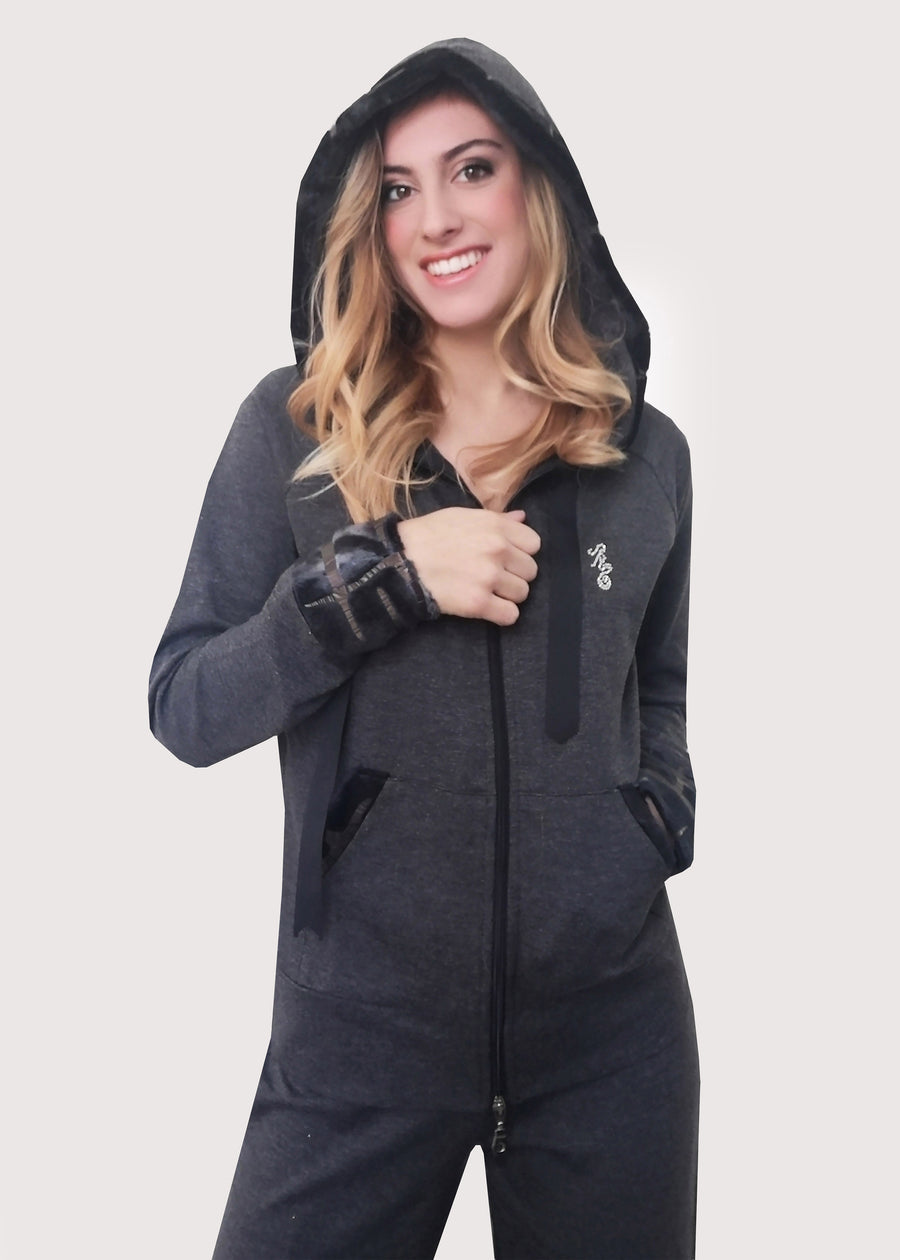 Tuta sportiva elegante grigia in calda viscosa stretch con cappuccio invernale. I bordi dei polsi e delle tasche sono in ecopelliccia. Un raffinato nastro in grogrè, è inserito nel bordo del cappuccio, per arricciarlo delicatamente. La tuta completo ha l'applicazione del logo Millyblu in strass. Il pantalone con elastico in vita è morbido e confortevole, dalla linea scivolata. 