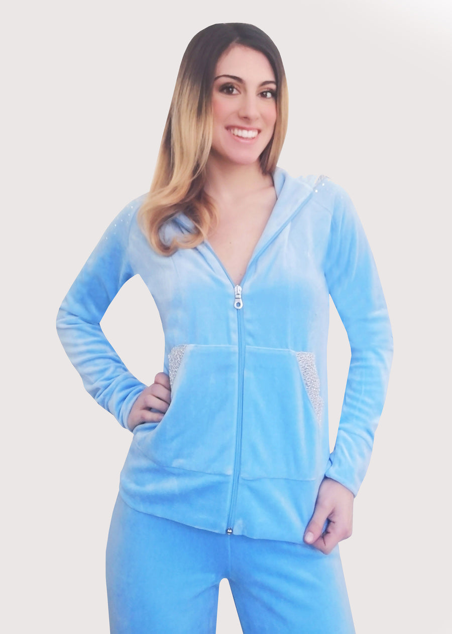 Tuta Completo in ciniglia celeste con inserti sulle tasche. La felpa con cappuccio è doppiata in maglina satinata cangiante. La tuta elegante ha la cerniera lampo. Il pantalone morbido ha l'elastico in vita e la coulisse all'orlo. 