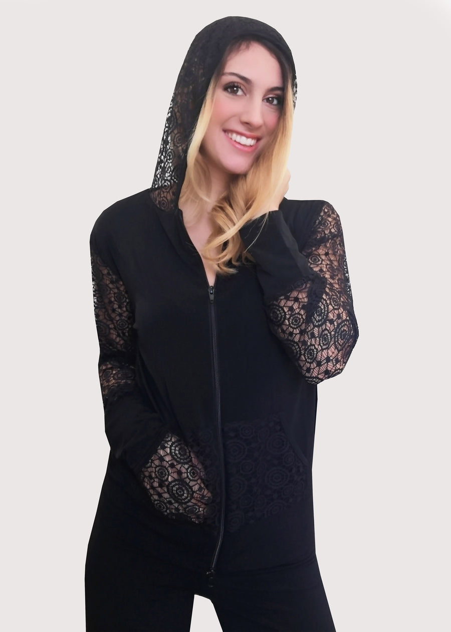 Tuta nera con inserti in pizzo e cappuccio in maglina elastica. La felpa, il cappuccio e le tasche in pizzo nello stesso colore abbinato e con la zip sul davanti ben rifinita. Il pantalone ha l'elastico e la doppia baschina in vita con un'ottima vestibilità che dona sinuosità alle forme femminili. Leggermente ampio all'orlo.
