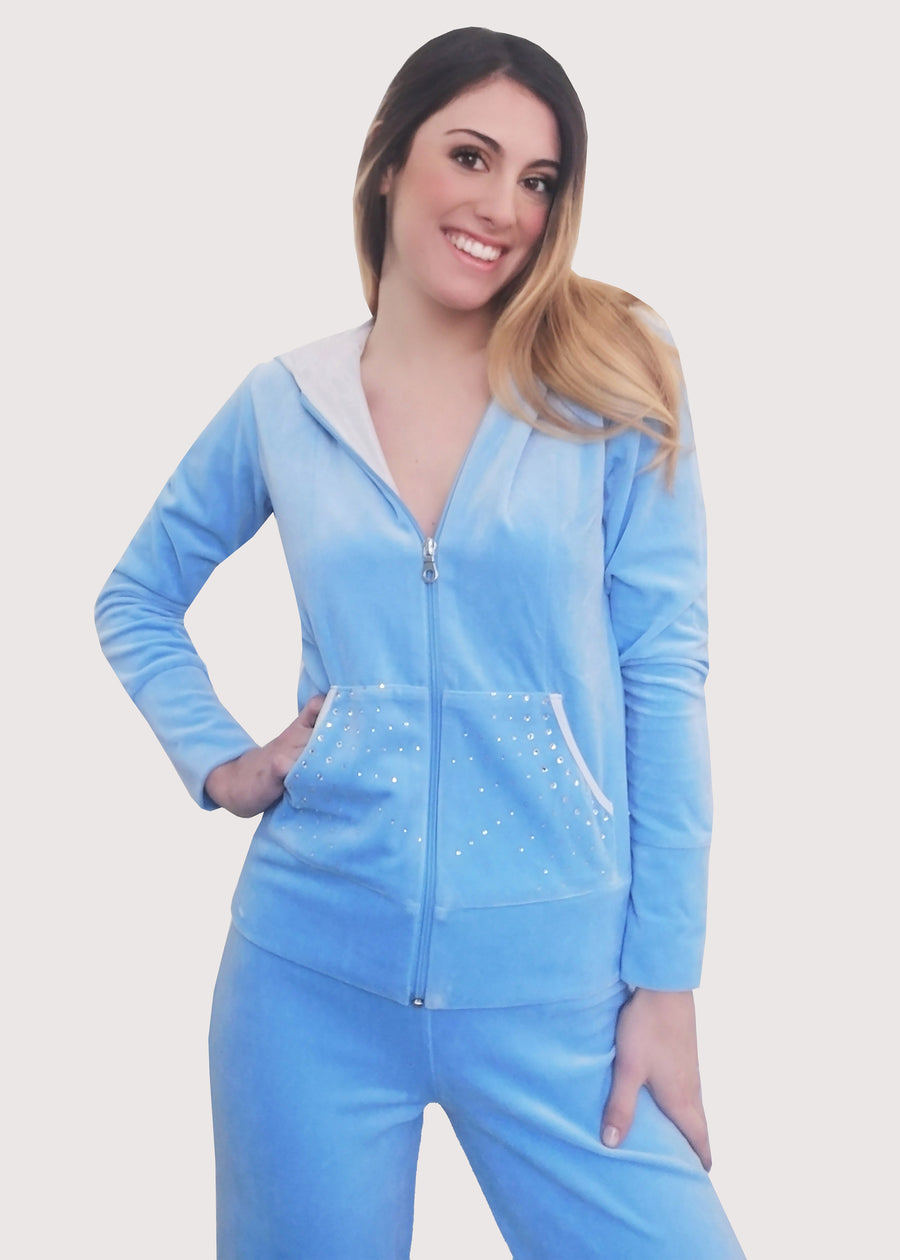 Tuta in ciniglia celeste elegante con strass sulle tasche e chiusura con zip sul davanti. L'interno del cappuccio è doppiato in maglina satinata cangiante. Pantalone jogging con l'elastico in vita e coulisse regolabile all'orlo. Ottima vestibilità.
