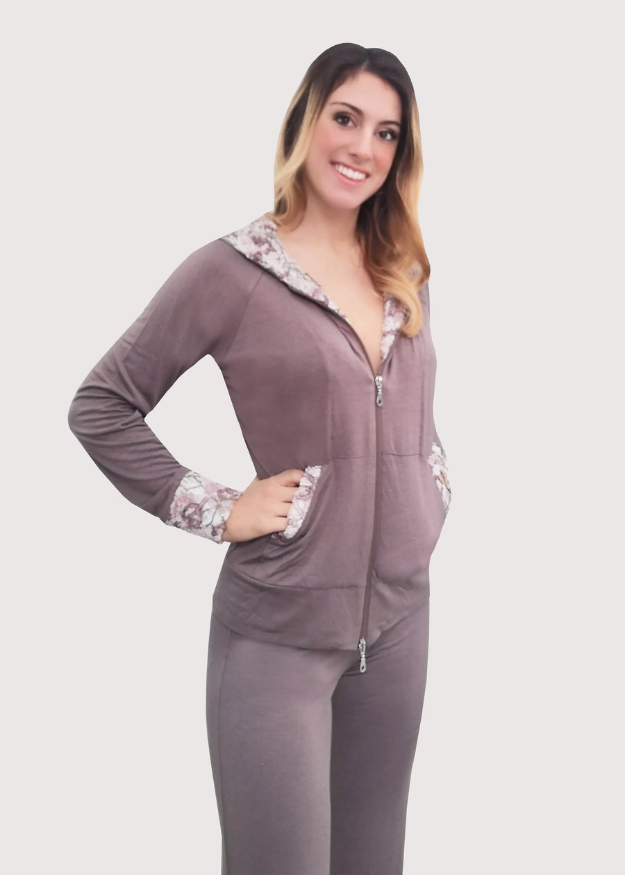 Tuta in viscosa elastica beige con cappuccio, polsi e tasche in pizzo dai disegni in rilievo panna e beige. Outfit mezza stagione. Il pantalone, con la baschina doppia e l'elastico inserito in vita, ha una linea leggermente ampia in fondo con la coulisse, che permette di regolare l'ampiezza e la lunghezza come meglio si desidera.