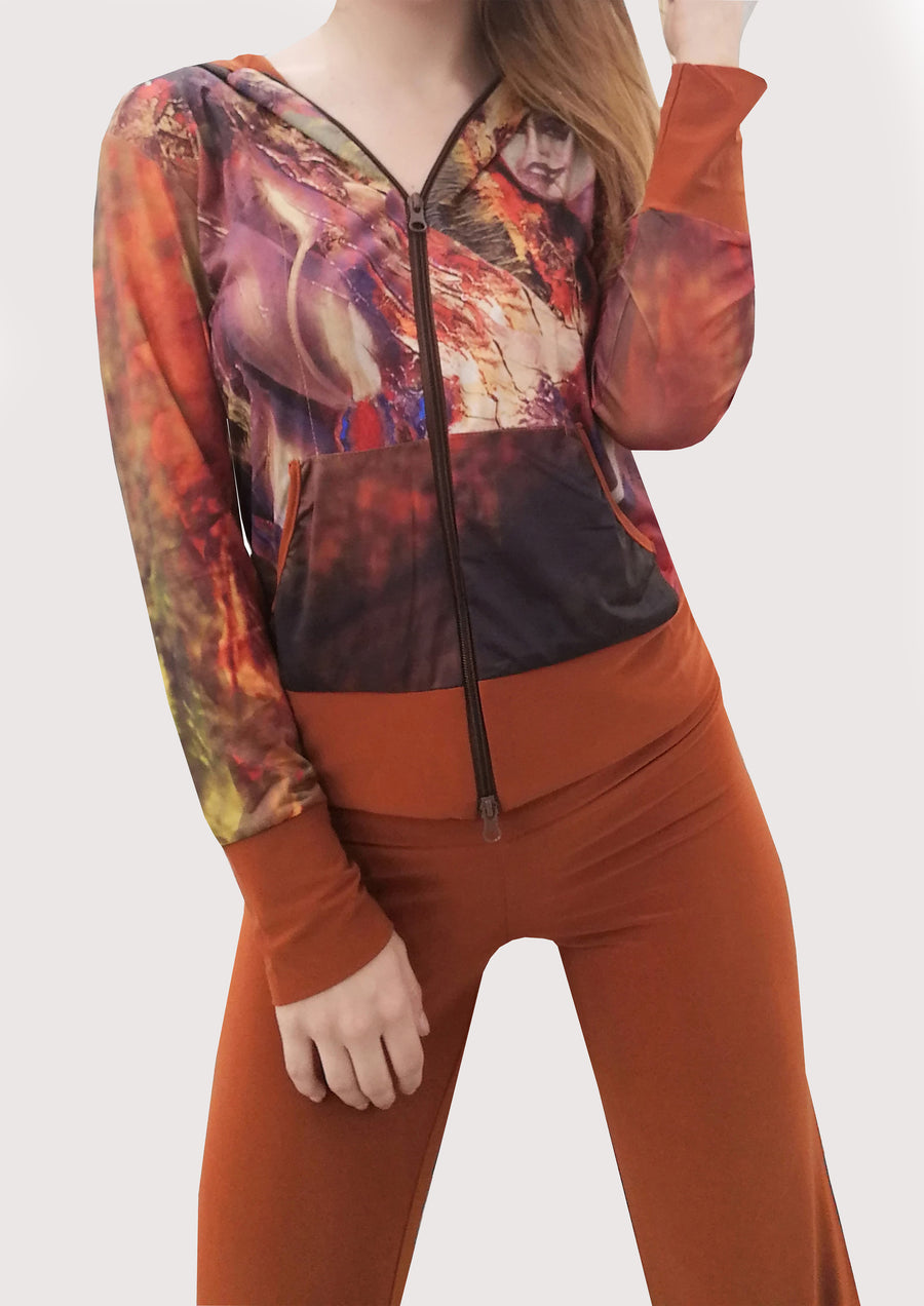 Tuta in maglina color coccio con cappuccio. Il giubbino riporta una delle nostre stampe, dal dipinto "Futura". Il pantalone è a tinta unita con la baschina doppiata e l'elastico in vita, dalla linea semplice e leggermente svasata in fondo. Particolare ed elegante nella sua essenza.