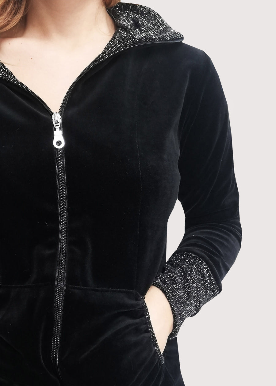 Tuta Completo nera in ciniglia senza cappuccio. La felpa con cerniera lampo ha il collo, le tasche e i polsi in lurex. Il pantalone morbido ha l'elastico in vita e coulisse sull'orlo per regolare l'ampiezza e la lunghezza come si preferisce.