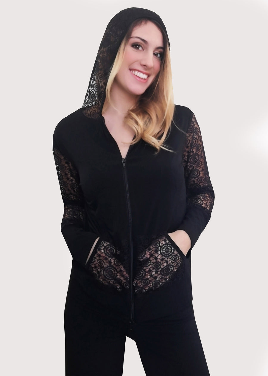 Tuta nera con inserti in pizzo e cappuccio in maglina elastica. La felpa, il cappuccio e le tasche in pizzo nello stesso colore abbinato e con la zip sul davanti ben rifinita. Il pantalone ha l'elastico e la doppia baschina in vita con un'ottima vestibilità che dona sinuosità alle forme femminili. Leggermente ampio all'orlo.