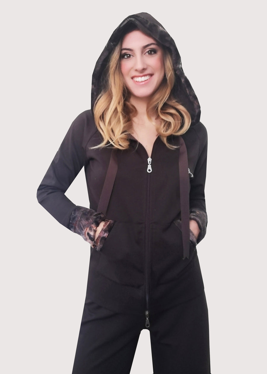 Tuta sportiva elegante marrone in calda viscosa stretch con cappuccio invernale. I bordi dei polsi e delle tasche sono in ecopelliccia. Un raffinato nastro in grogrè, è inserito nel bordo del cappuccio, per arricciarlo delicatamente. La tuta completo ha l'applicazione del logo Millyblu in strass. Il pantalone con elastico in vita è morbido e confortevole, dalla linea scivolata. 