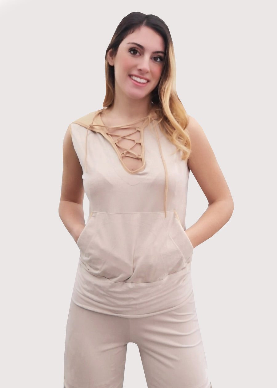 Tuta Completo in dainetto stretch con cappuccio foderato in jersey satinato. Scollo a V con lacci incrociati, senza maniche e tasche a marsupio. Il pantalone con elastico in vita, ha la coulisse sull'orlo per poterlo regolare come si desidera. Il budellino inserito sui lati del pantalone, crea un fiocco, donando movimento alla silhouette.