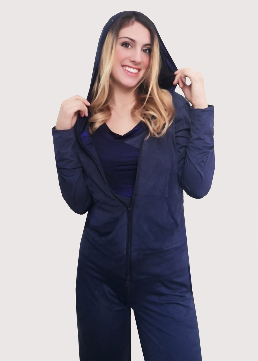 Tuta Completo in dainetto stretch con inserti in maglina satinata blu nel cappuccio e lungo i bordi delle tasche. La tuta completo comprende giubbino, maglia a maniche corte e pantalone. Il pantalone con elastico in vita ha le tasche con taglio a mezzaluna e le coulisse regolabili alla caviglia.