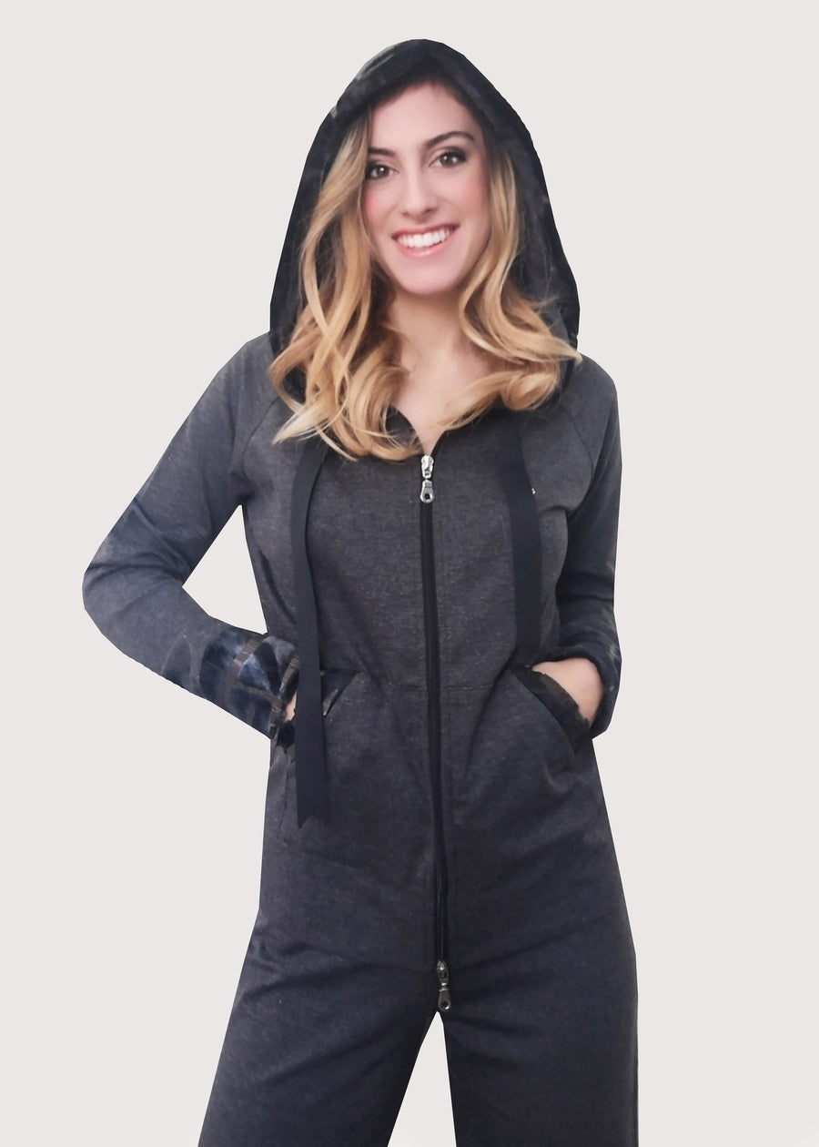 Tuta sportiva elegante grigia in calda viscosa stretch con cappuccio invernale. I bordi dei polsi e delle tasche sono in ecopelliccia. Un raffinato nastro in grogrè, è inserito nel bordo del cappuccio, per arricciarlo delicatamente. La tuta completo ha l'applicazione del logo Millyblu in strass. Il pantalone con elastico in vita è morbido e confortevole, dalla linea scivolata. 