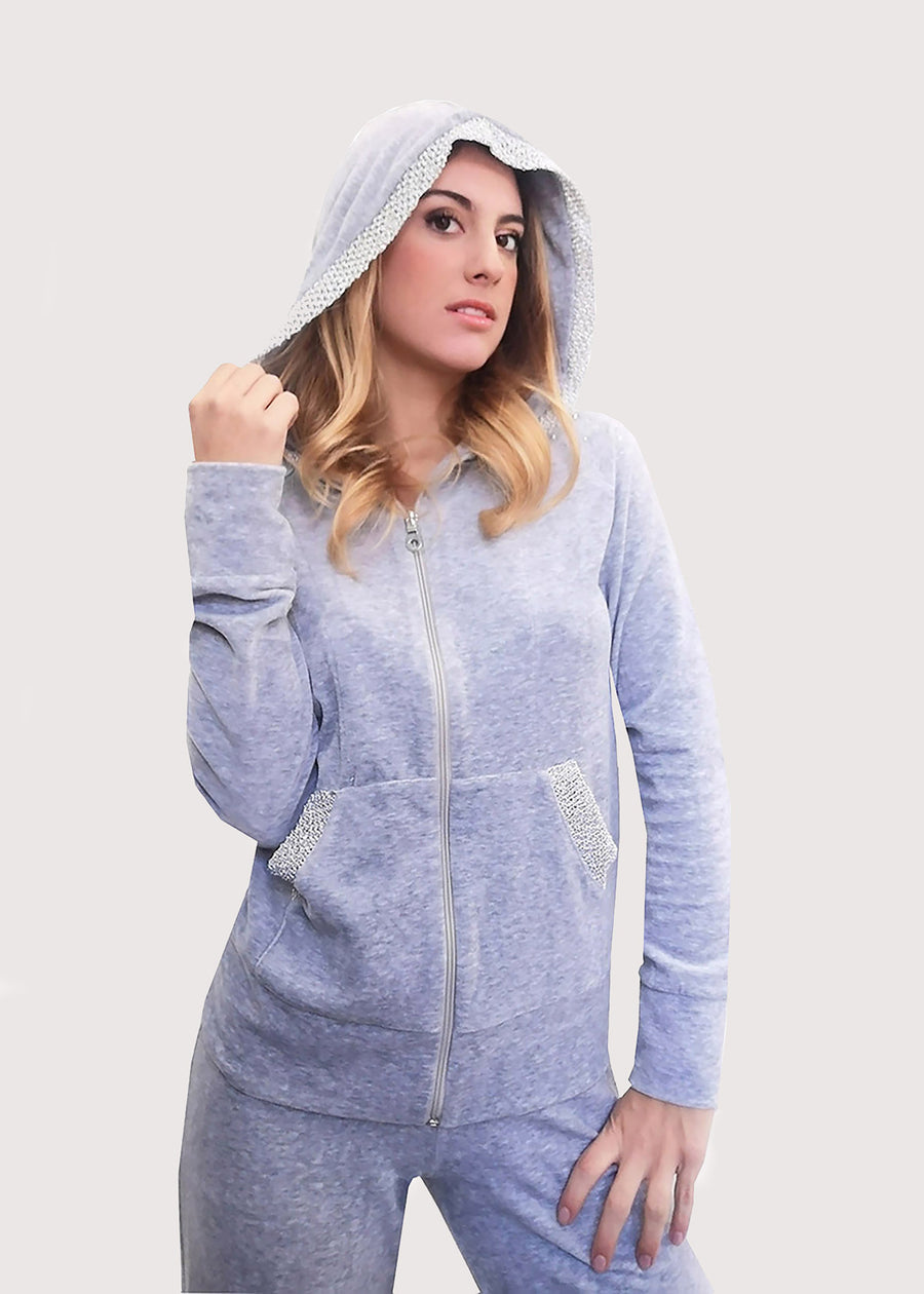 Tuta Completo in ciniglia grigia con inserti sulle tasche. La felpa con cappuccio è doppiata in maglina satinata cangiante. La tuta elegante ha la cerniera lampo. Il pantalone morbido ha l'elastico in vita e la coulisse all'orlo. 
