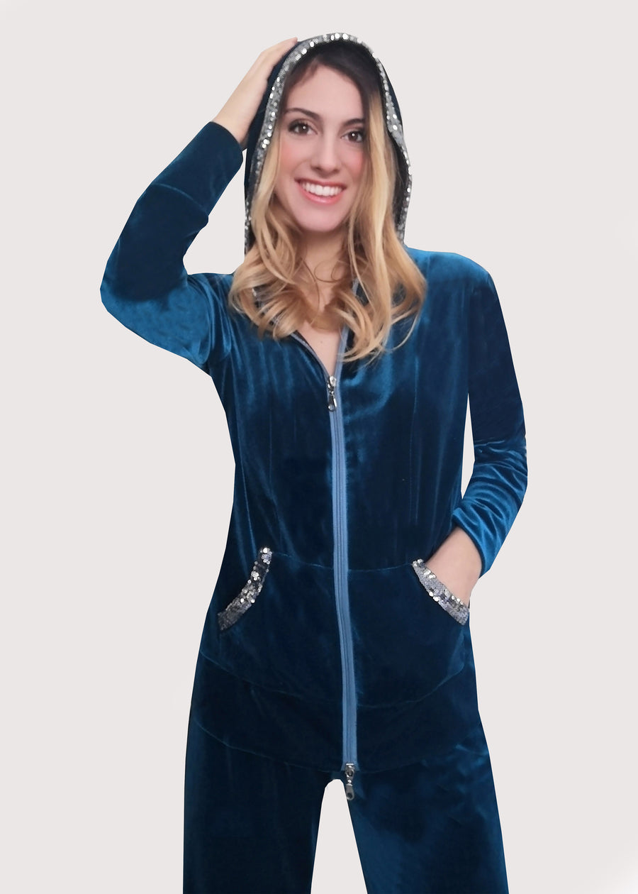 Tuta Completo in velluto stretch verde smeraldo con l'interno del cappuccio ed i bordi in paillettes argento. La felpa con cappuccio ha la cerniera lampo e il pantalone morbido con l'elastico in vita. La vestibilità è comoda, confortevole ed elegante.