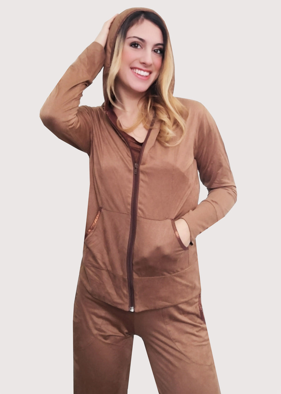 Tuta Sportiva Elegante in dainetto stretch con inserti satinati sui toni del cuoio e inserti in maglina satinata nel cappuccio e lungo i bordi delle tasche. La tuta completo comprende giubbino, maglia a maniche corte e pantalone. Il pantalone con elastico in vita ha le tasche con taglio a mezzaluna e le coulisse regolabili alla caviglia.