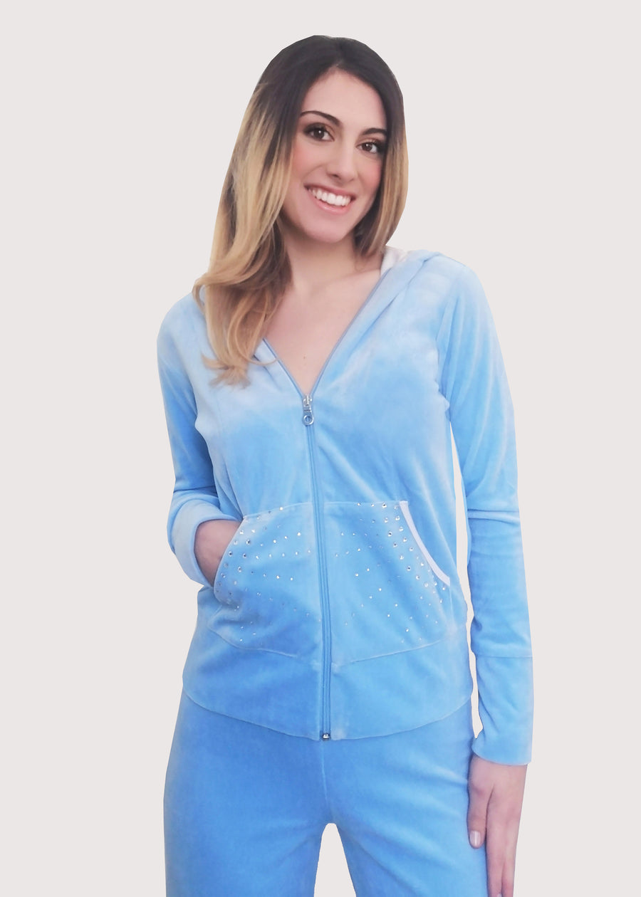 Tuta in ciniglia celeste elegante con strass sulle tasche e chiusura con zip sul davanti. L'interno del cappuccio è doppiato in maglina satinata cangiante. Pantalone jogging con l'elastico in vita e coulisse regolabile all'orlo. Ottima vestibilità.