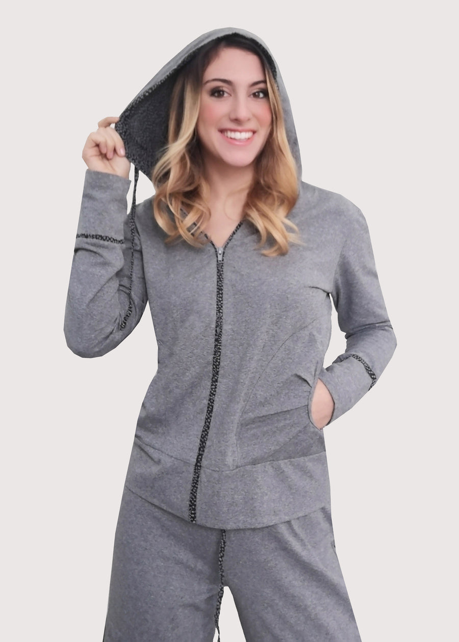 Tuta grigia in cotone elastico, morbido e confortevole. La felpa ha le tasche e l'apertura a zip. Il cappuccio e i buddelini riportano una fantasia delicata. Il pantalone ha le tasche posteriori e dei budellini fantasia lateralmente. 