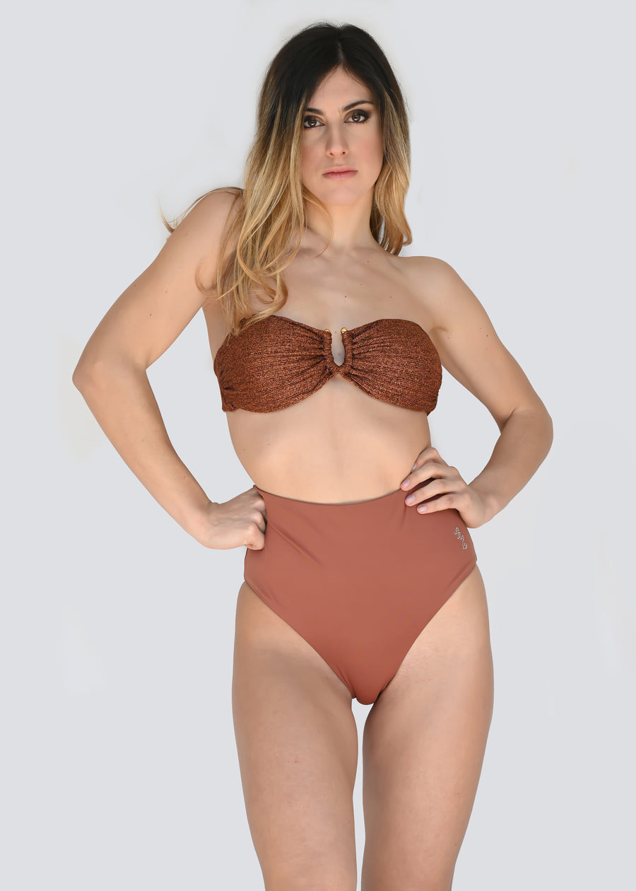 Bikini a fascia coccio e lurex bronzo con fodera e laccetti coccio, dai dettagli chic e sofisticati. La fascia è impreziosita da un anello centrale a "U" color oro nichel free, coppe estraibili e laccetti elastici che possono essere annodati dietro al collo, ma anche utilizzati come bretelline. Lo slip a vita alta double face e può essere utilizzato anche ripiegandolo su se stesso.
