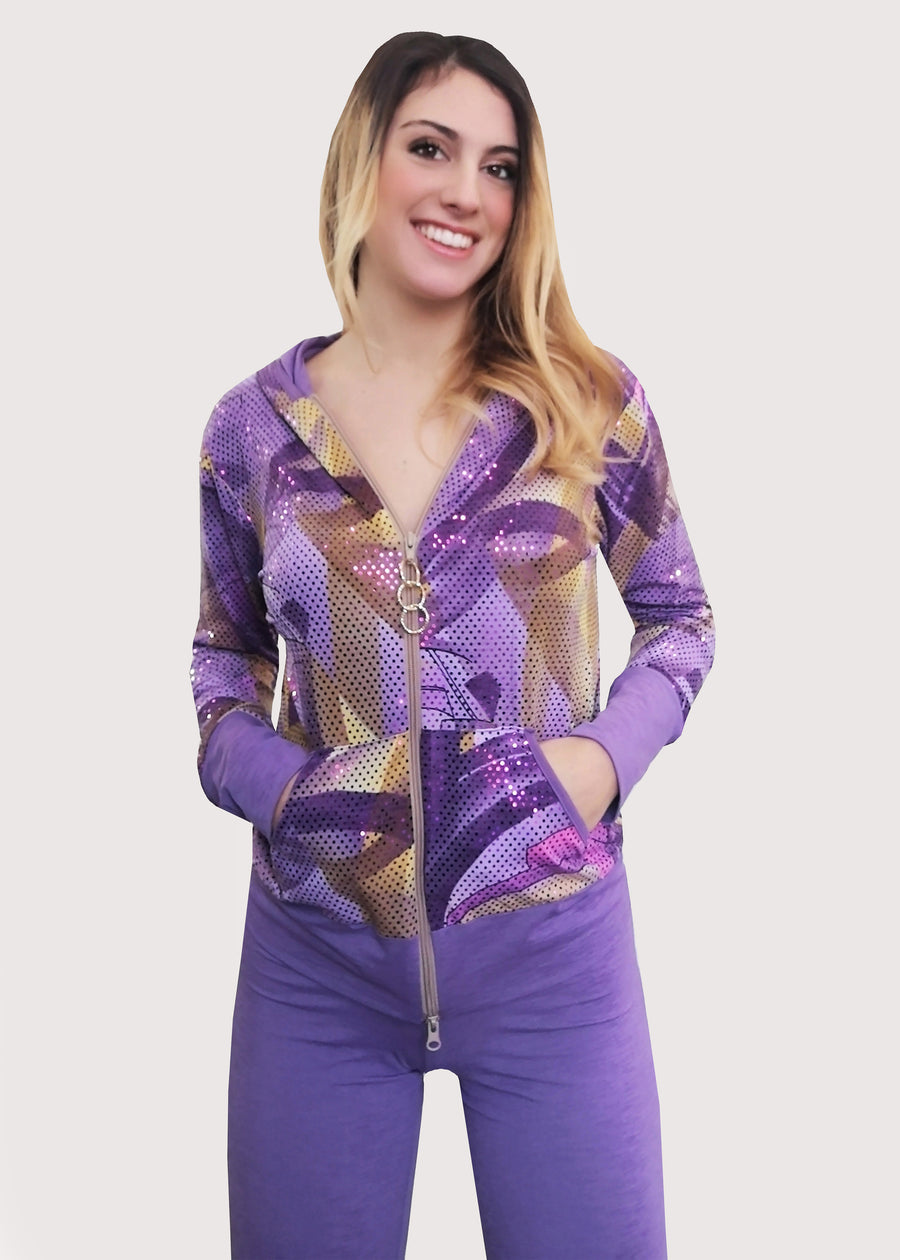 Tuta lilla in maglina e paillettes fantasia, con cinta, polsi e interno del cappuccio in maglina rivestita di stampa in paillettes. Il pantalone è semplice e scivola dritto, ampio alla caviglia, con elastico in vita.