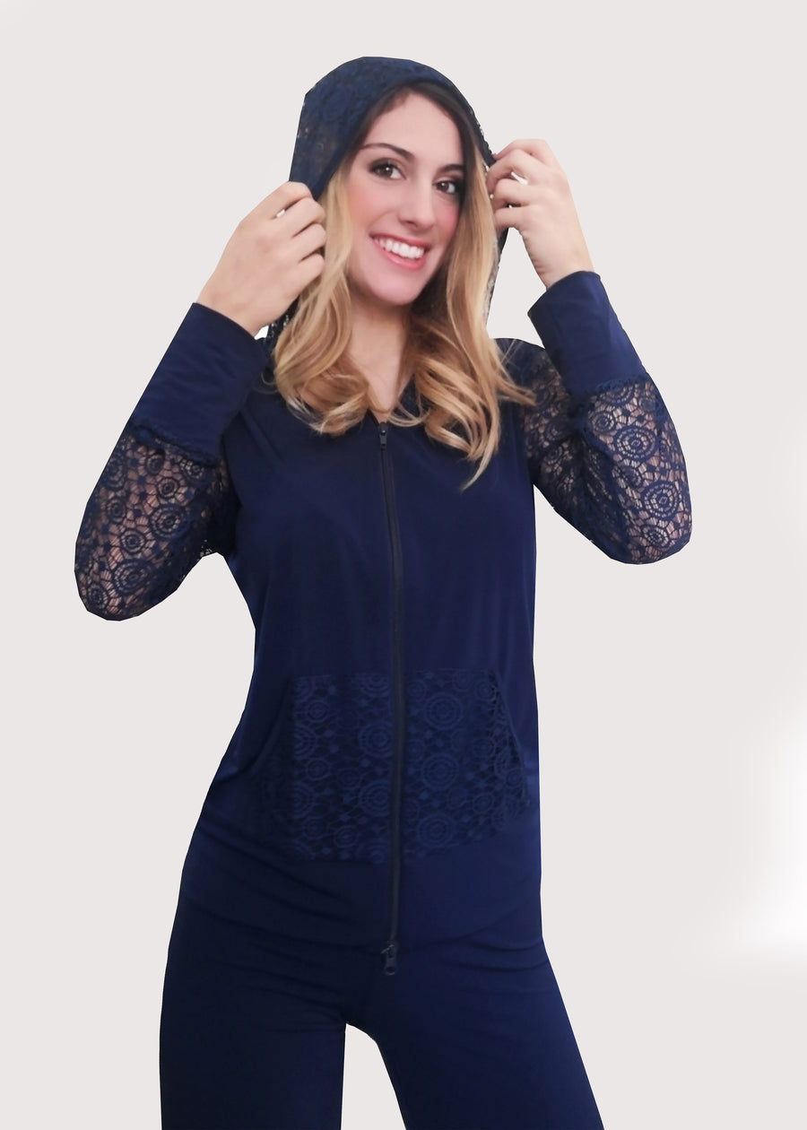 Tuta blu con inserti in pizzo e cappuccio in maglina elastica. La felpa, il cappuccio e le tasche sono in pizzo, nello stesso colore abbinato e con la zip sul davanti. Il pantalone ha l'elastico e la doppia baschina in vita con un'ottima vestibilità che dona sinuosità alle forme femminili. Leggermente ampio all'orlo.