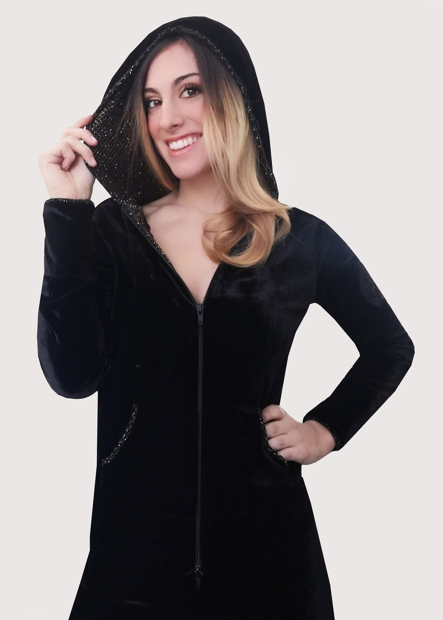 Completo tuta elegante in velluto nero. La tuta con cappuccio ha la cerniera lampo e lo stemma ricamato sulla manica. Gli interni della tuta sono in maglina lurex oro. Il pantalone morbido in velluto nero ha l'elastico in vita e la coulisse regolabile inserita nell'orlo.