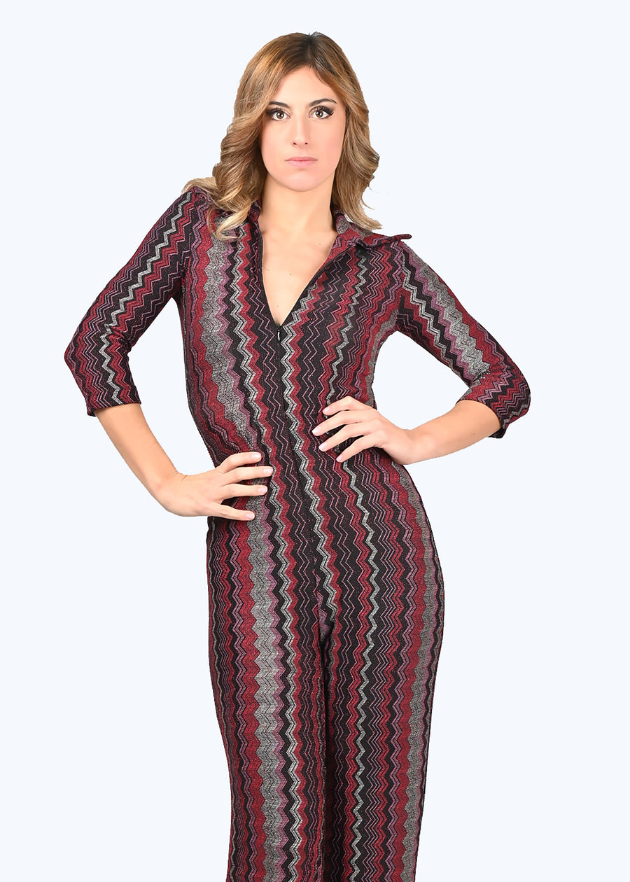 Tuta intera elegante Elena in lurex geometrico rosso. La profondità della scollatura è regolabile, grazie alla zip invisibile. La manica della tuta è a 3/4. Il modello è a vita alta con pantalone dalla linea scivolata.