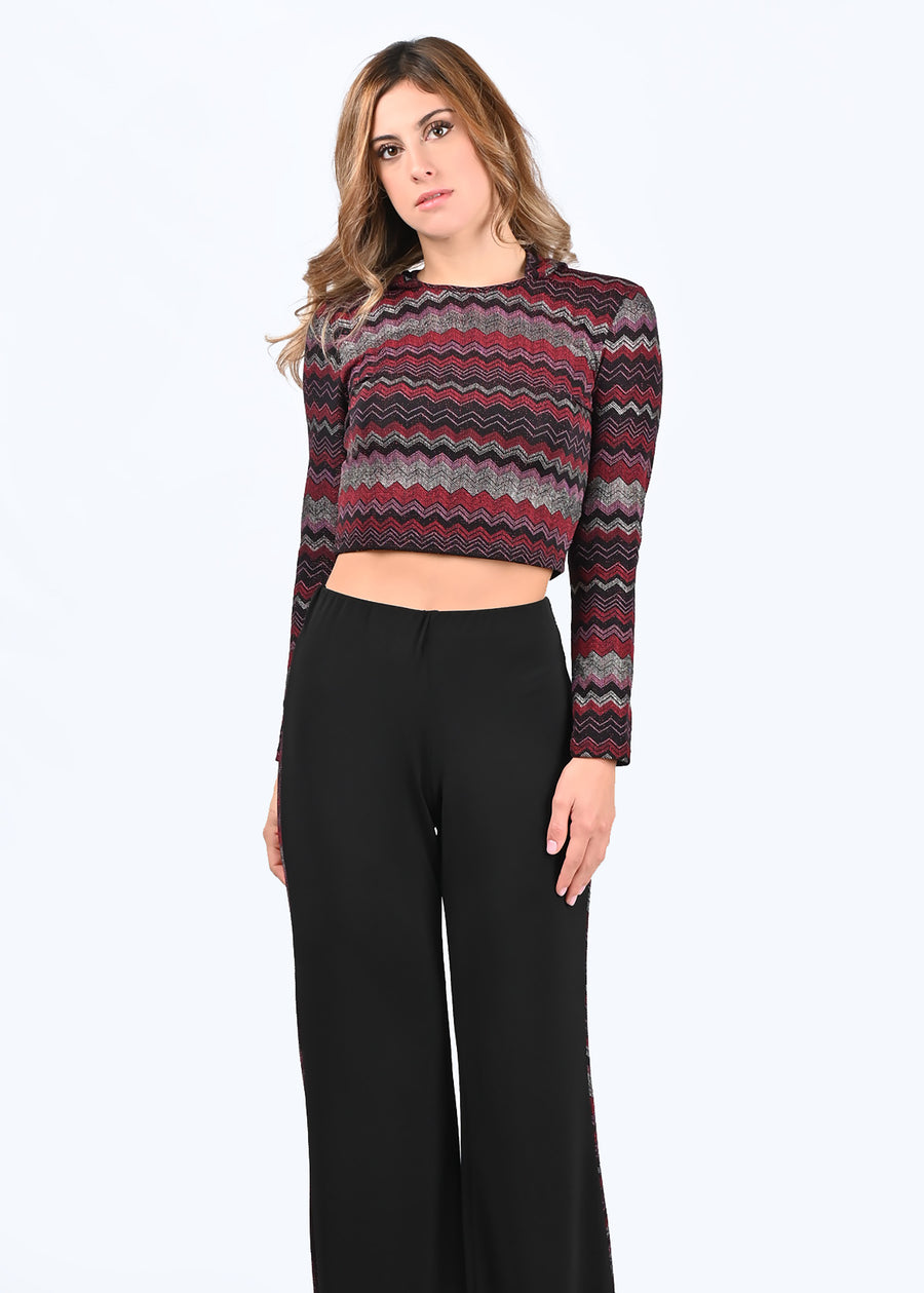 Tuta Completo Melissa con disegni geometrici in lurex rosso. Il top è morbido e confortevole, con la manica lunga e la scollatura a girocollo. Il cappuccio dona al capo un'aria più fresca, sportiva e moderna. Il pantalone in crepe è morbido, a vita alta con elastico in vita. La riga laterale riprende la fantasia del top, slanciando e allungando maggiormente la figura femminile.