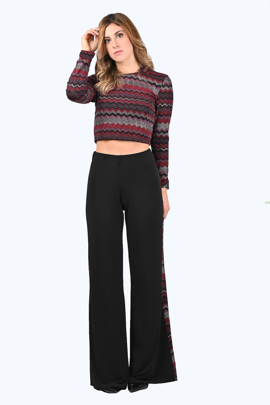 Tuta Completo Melissa con disegni geometrici in lurex rosso. Il top è morbido e confortevole, con la manica lunga e la scollatura a girocollo. Il cappuccio dona al capo un'aria più fresca, sportiva e moderna. Il pantalone in crepe è morbido, a vita alta con elastico in vita. La riga laterale riprende la fantasia del top, slanciando e allungando maggiormente la figura femminile.